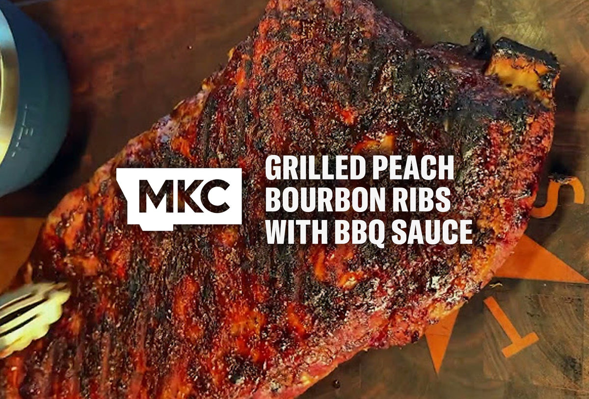 Grilled ribs with a dark caramelized crust on a wooden board, coated in glossy peach‑bourbon barbecue sauce.