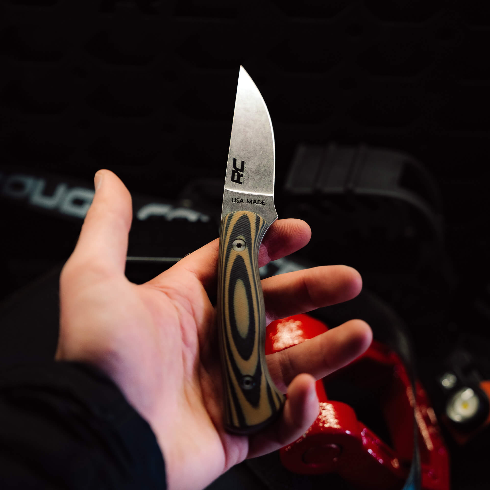 Hand holding the Rough Country Magnacut Blackfoot 2.0 knife, featuring a sleek blade and patterned handle, USA made.