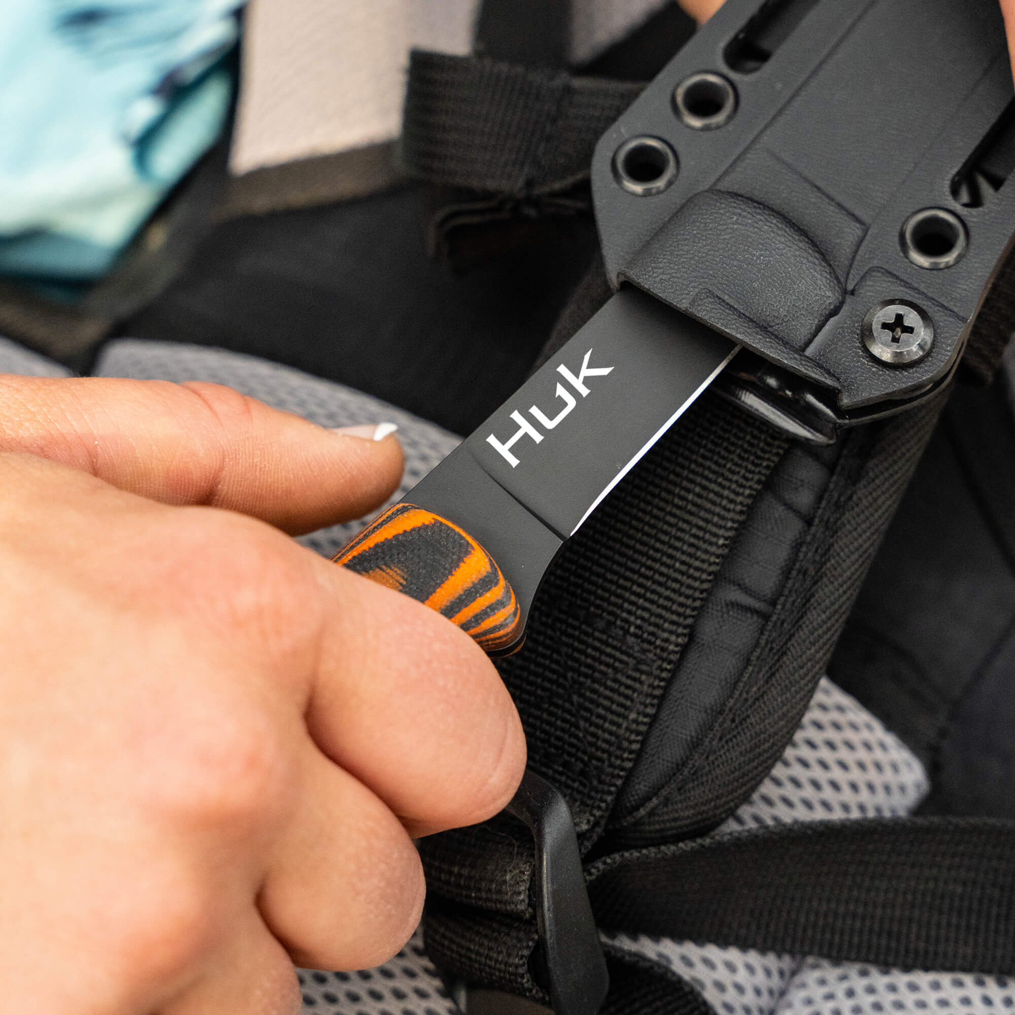 HUK Flathead Fillet knife being sheathed, showcasing its durable design and ergonomic handle for fishing enthusiasts.