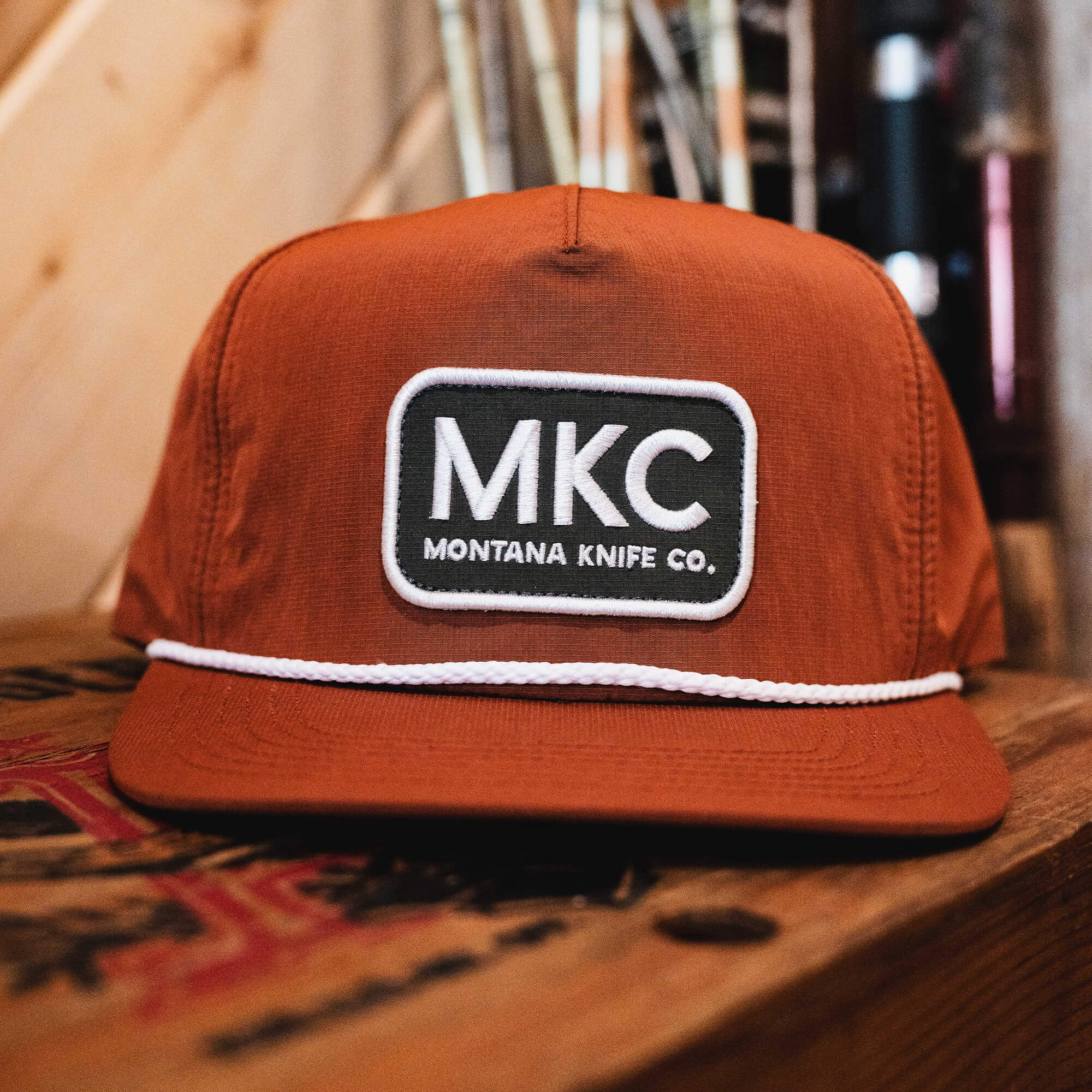 Rust-colored MKC River Rope Hat featuring a prominent Montana Knife Company logo and a decorative rope detail.