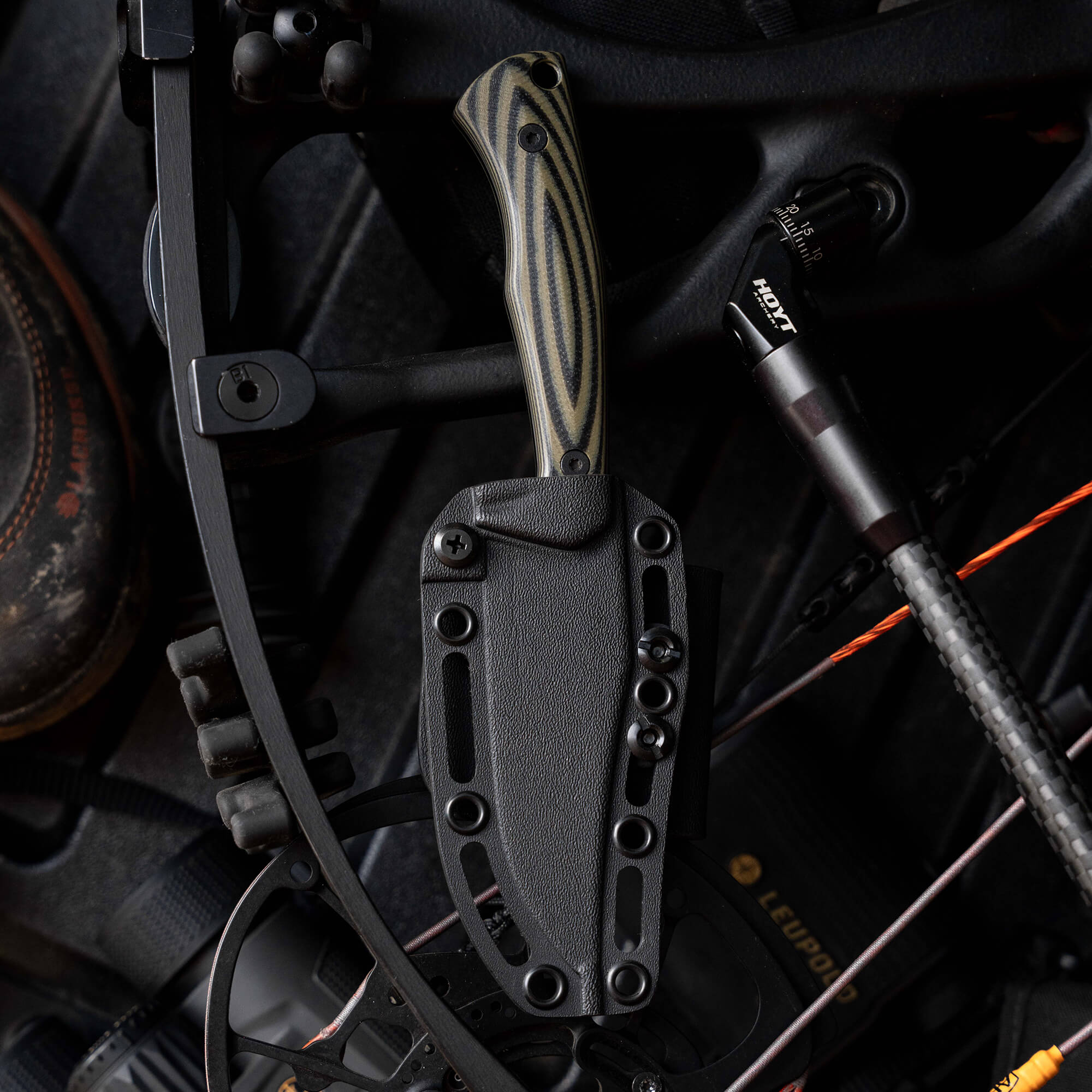Montana Knife Company's Nock On Triumph Pro knife displayed on a bow, featuring a sleek design and durable sheath.