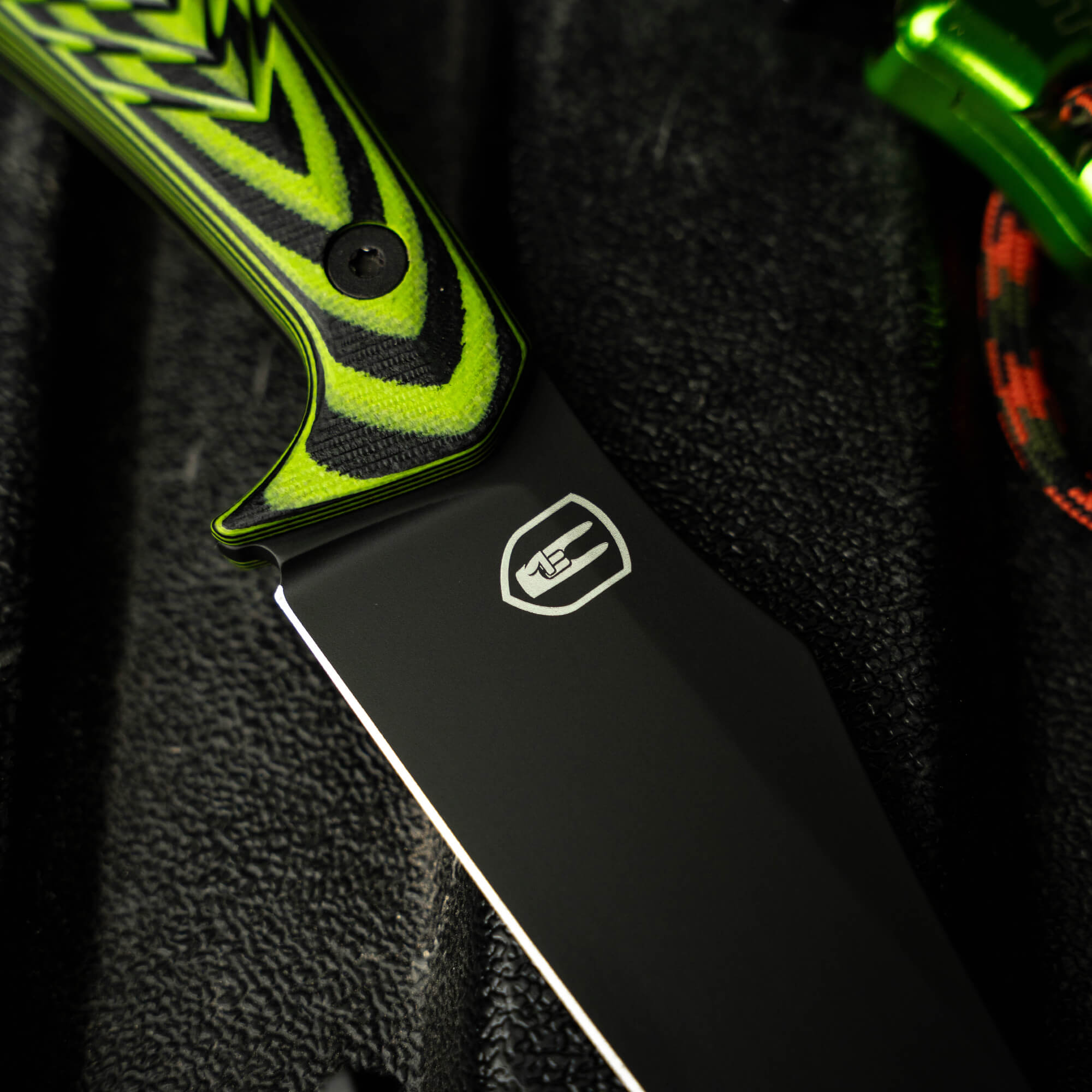 Close-up of the NOCK ON Triumph Pro knife blade featuring a sleek black finish and vibrant green handle design.