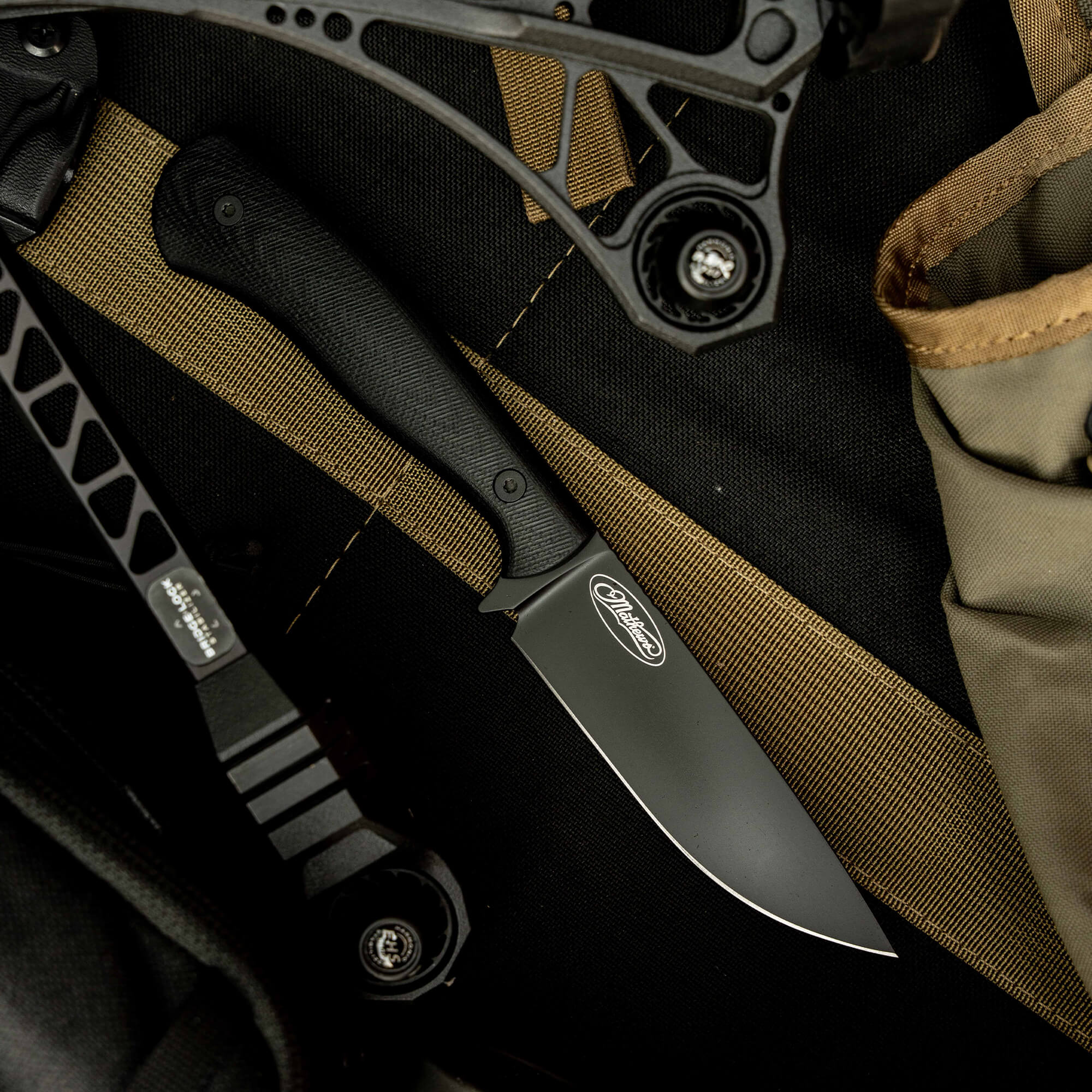 Mathews Archery MKC Whitetail knife featuring a sleek black blade and ergonomic handle, set against a tactical background.