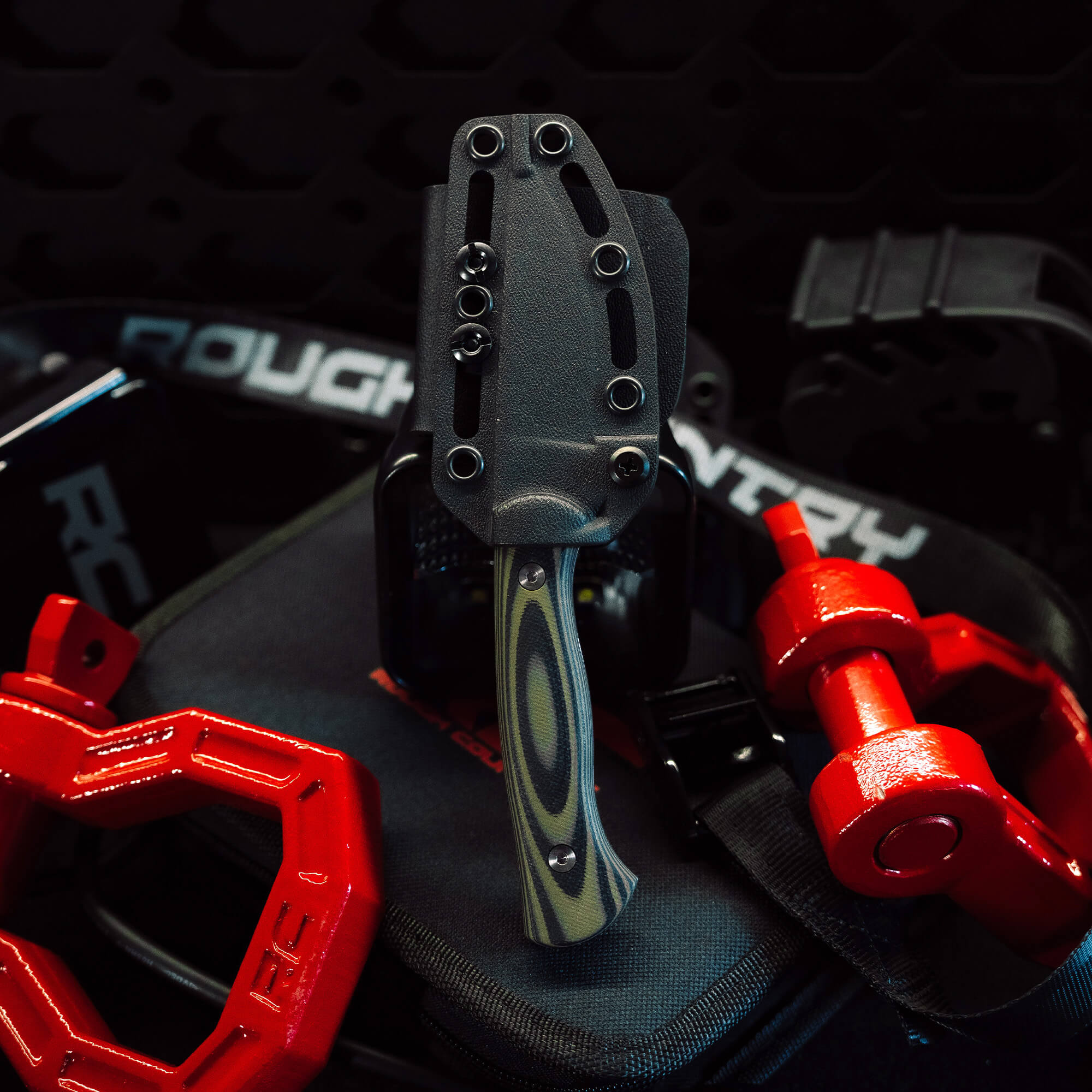 Rough Country Magnacut Blackfoot 2.0 knife displayed with red weights and gear, showcasing its rugged design and functionality.