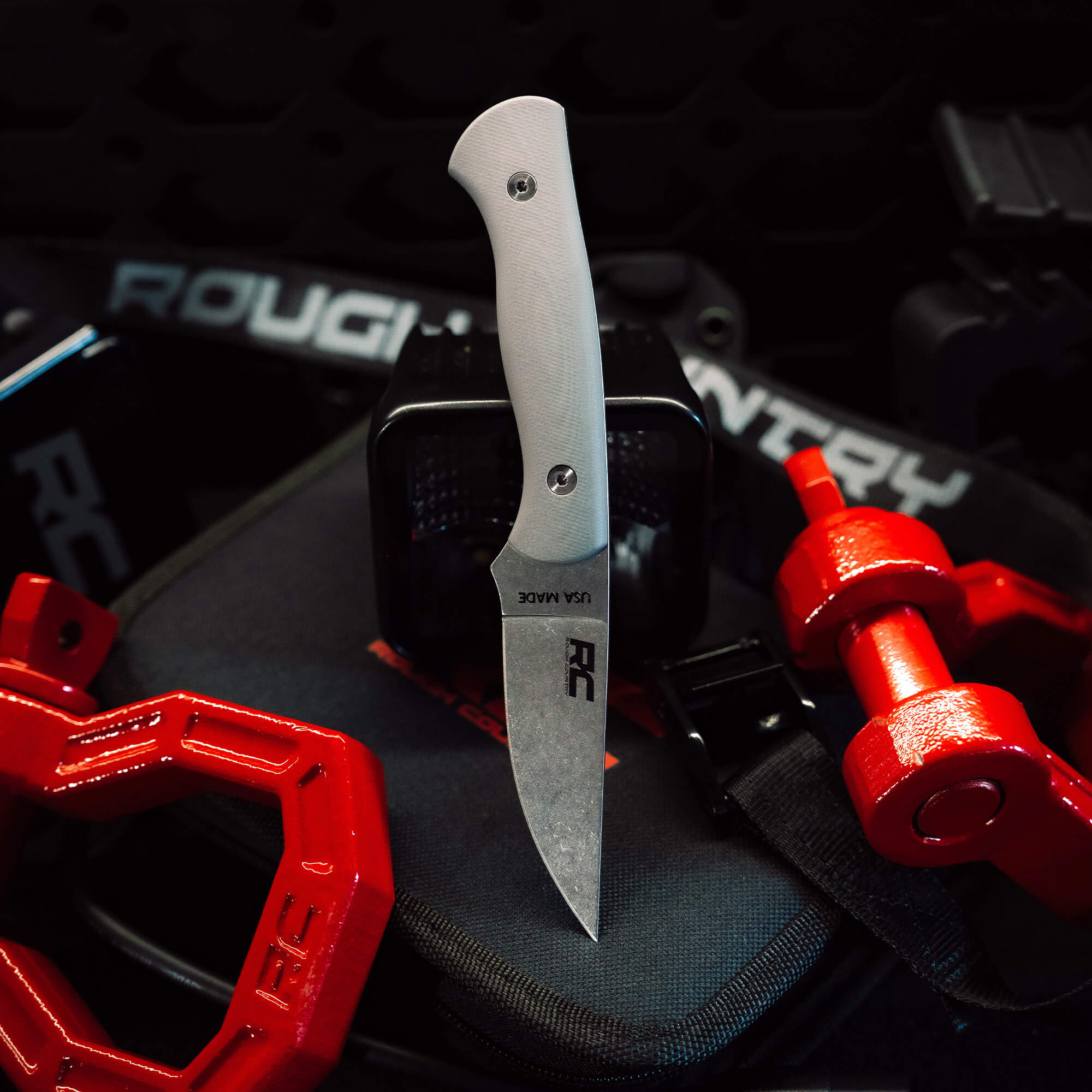 Rough Country Magnacut Blackfoot 2.0 knife displayed on a gear background, showcasing its sleek design and durable blade.