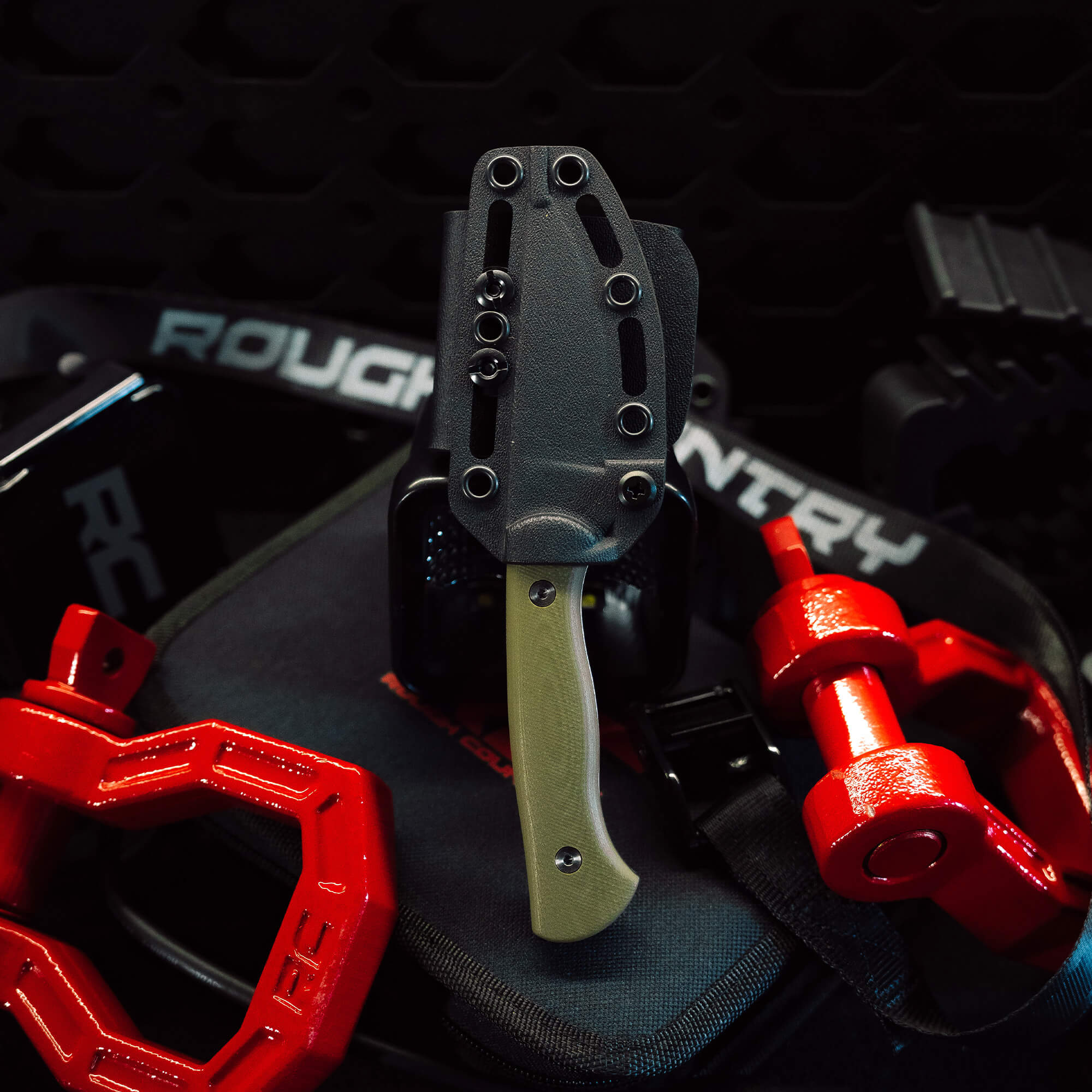 Rough Country Magnacut Blackfoot 2.0 knife displayed on a gym bench with weights, showcasing its durable design and functionality.