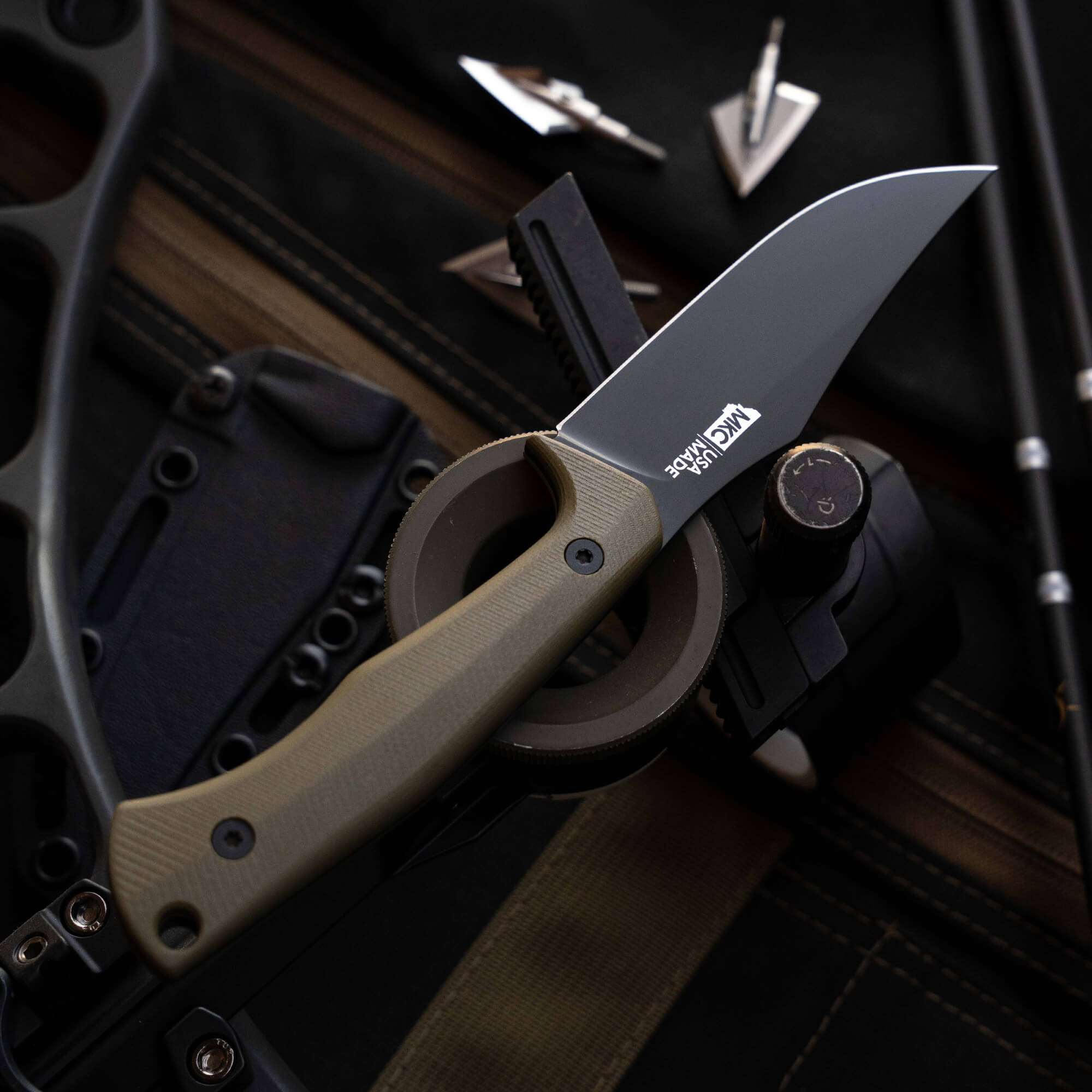 Montana Knife Company Triumph Pro knife with a sleek blade and olive drab handle, displayed on a tactical background.