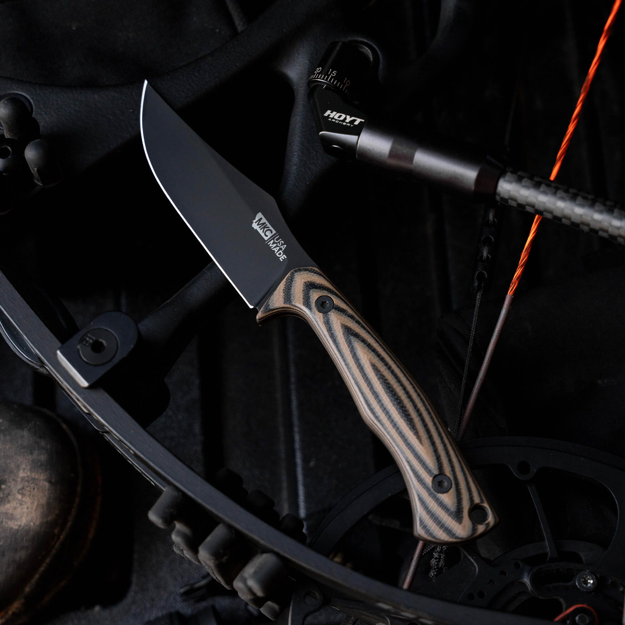 Montana Knife Company's Nock On Triumph Pro knife features a sleek black blade and a textured handle, ideal for outdoor use.