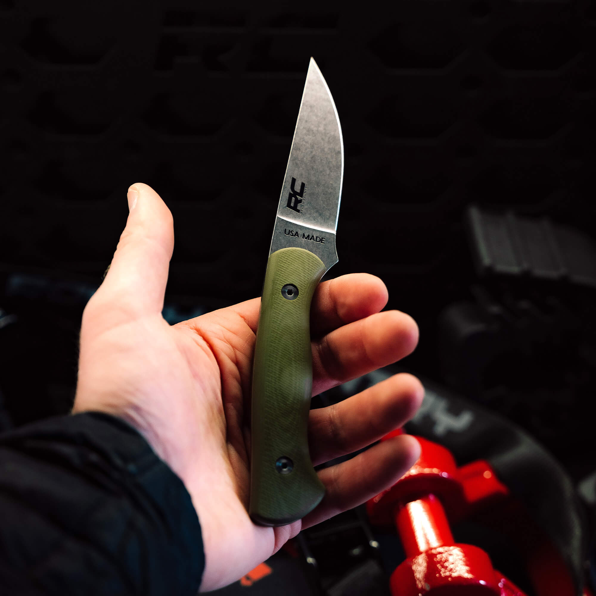 Hand holding the Rough Country Magnacut Blackfoot 2.0 knife featuring a sleek blade and green handle, showcasing American craftsmanship.