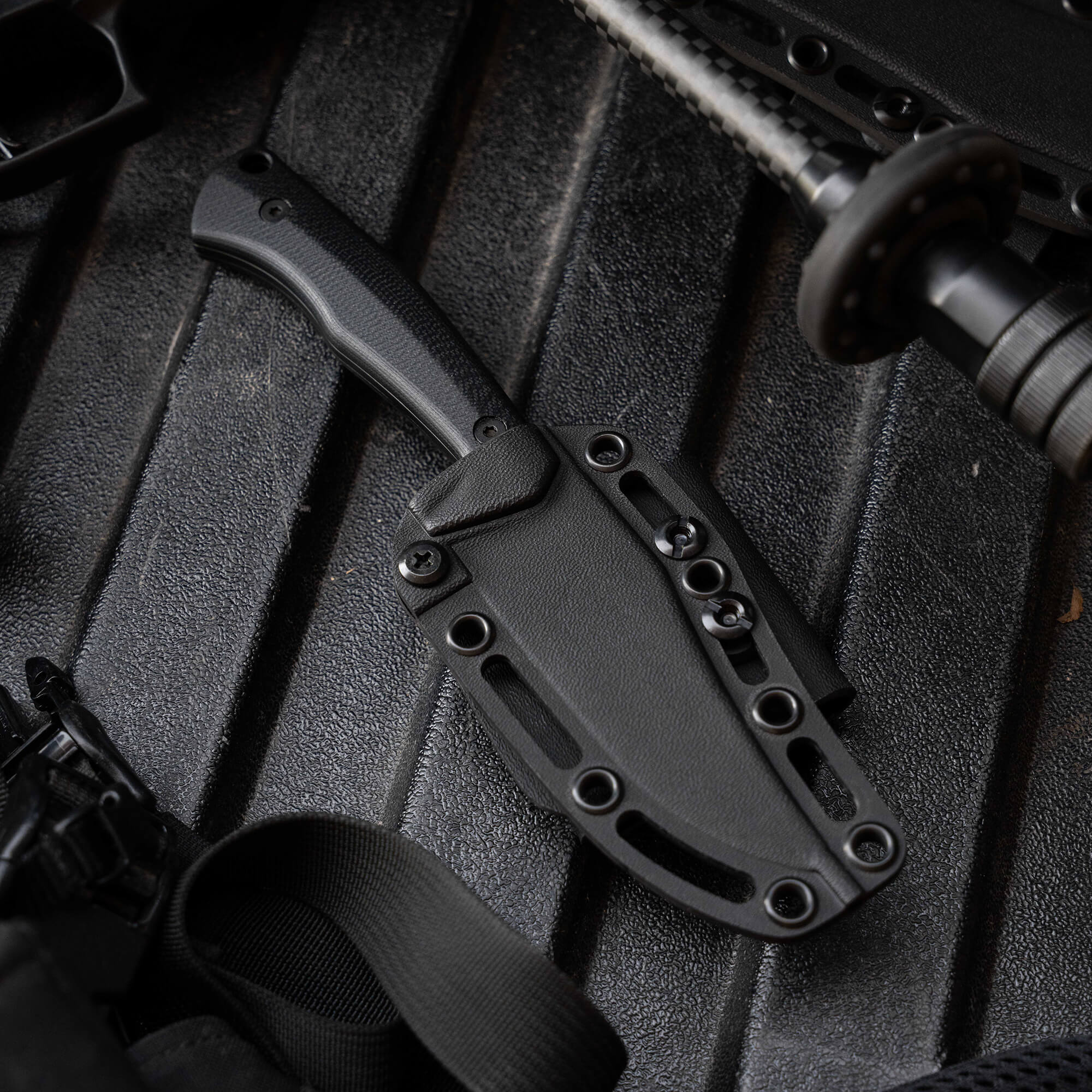 Black fixed-blade knife with a textured handle and sheath, showcasing rugged design for outdoor use.