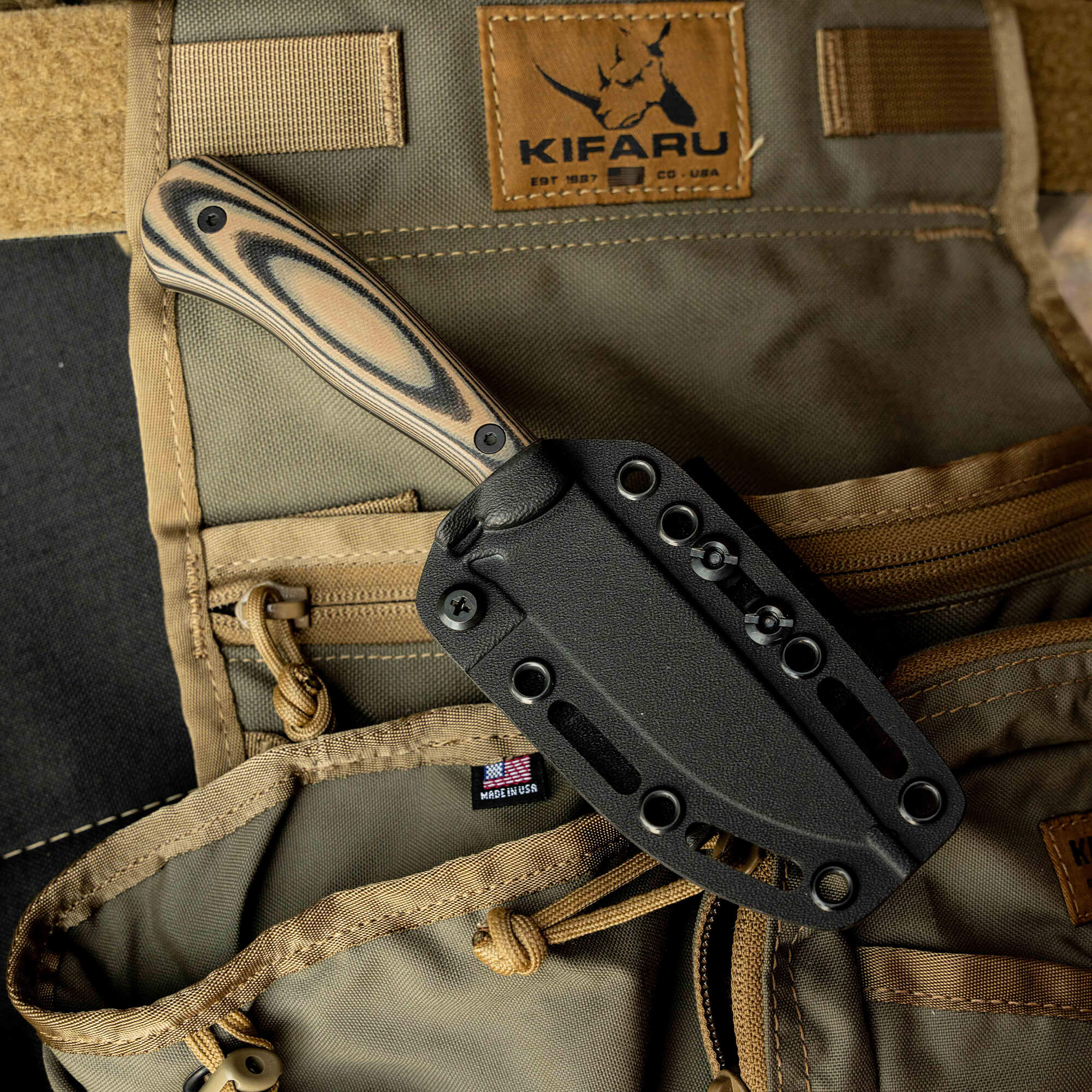 Mathews Archery MKC Whitetail knife in sheath, featuring a textured handle, resting on tactical gear.