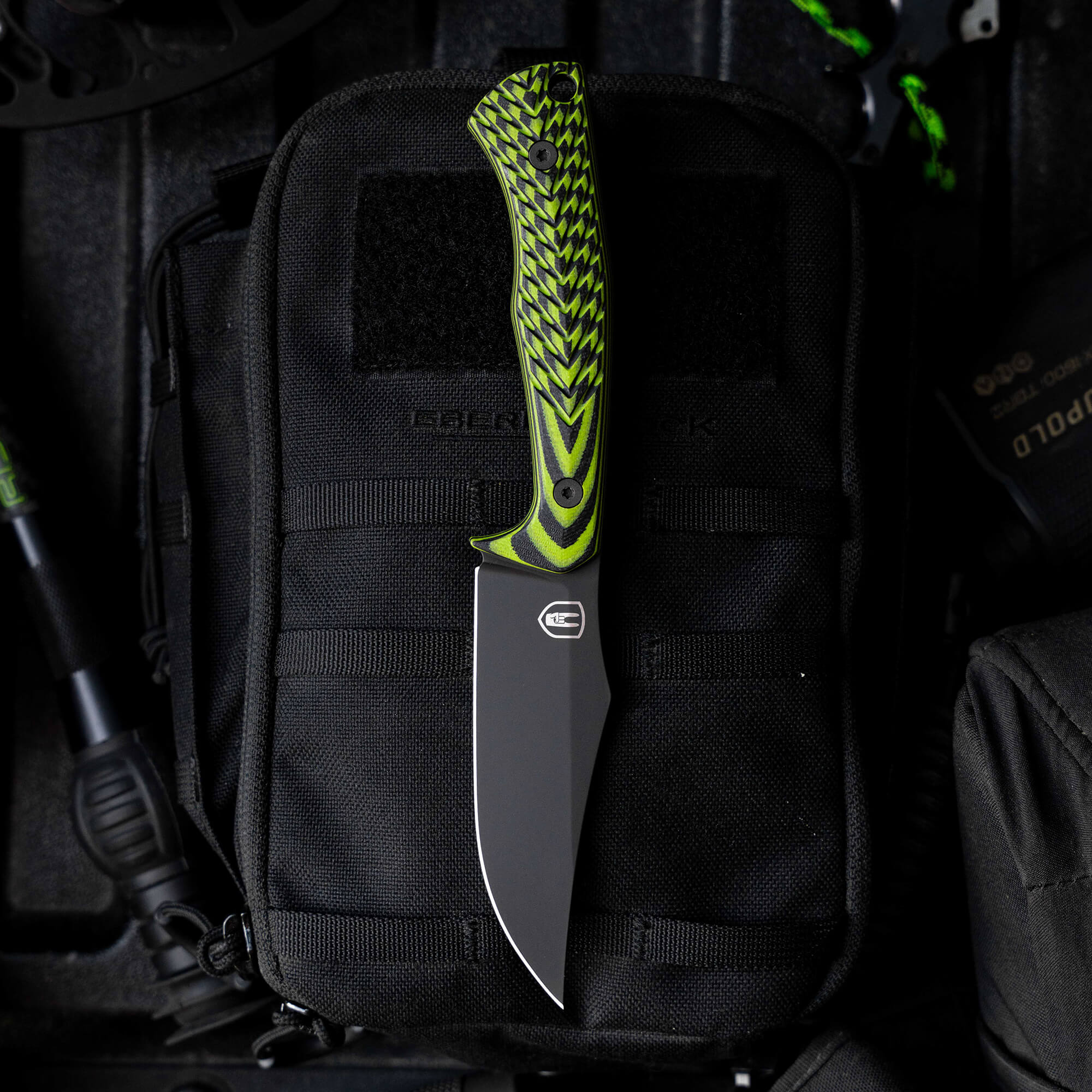 Montana Knife Company's Nock On Triumph Pro knife with a vibrant green and black handle, resting on a tactical pouch.